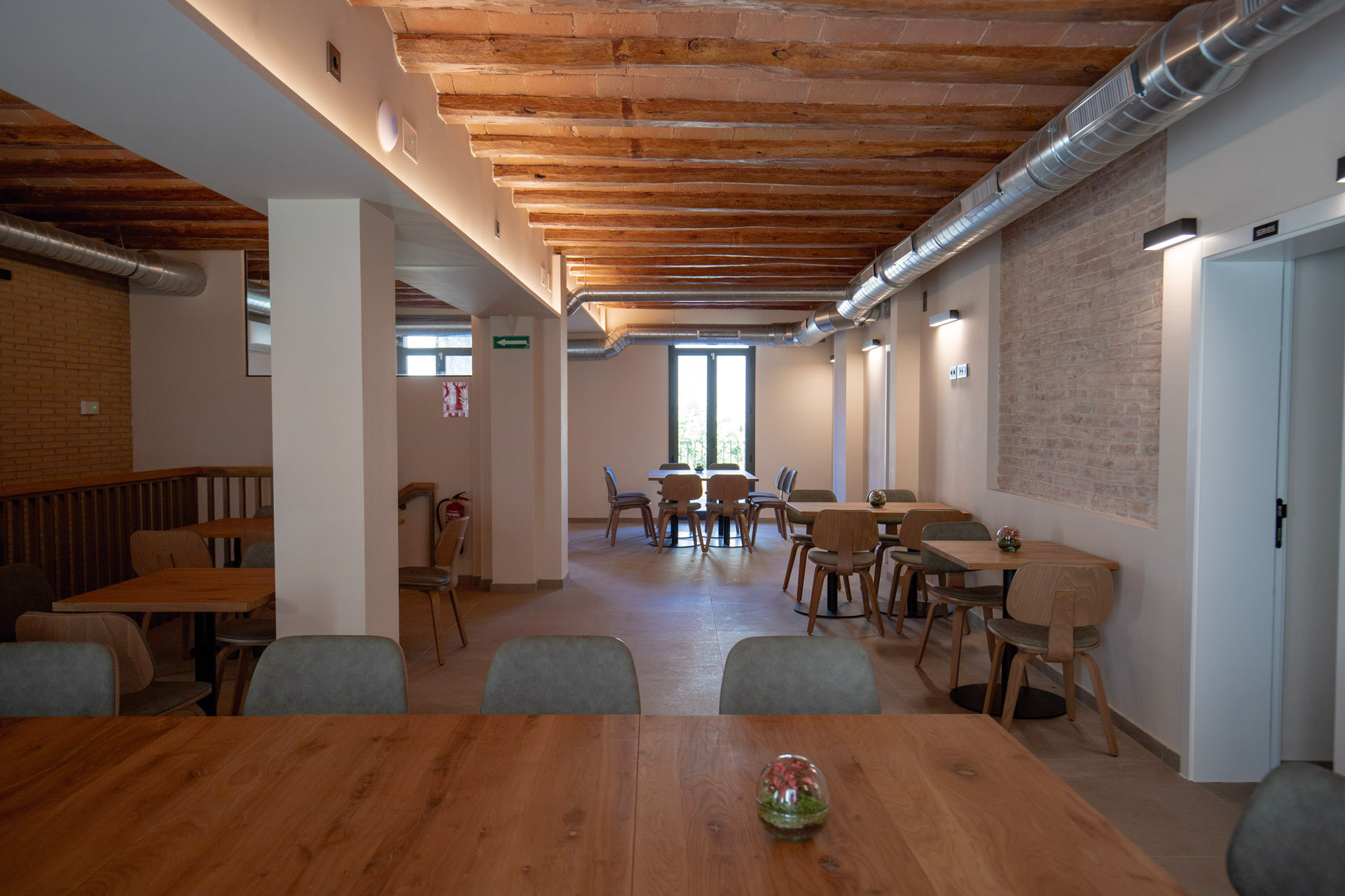 Luminaria de pared y tira led iluminan indirectamente la sala de un restaurante de forma suave y sutil